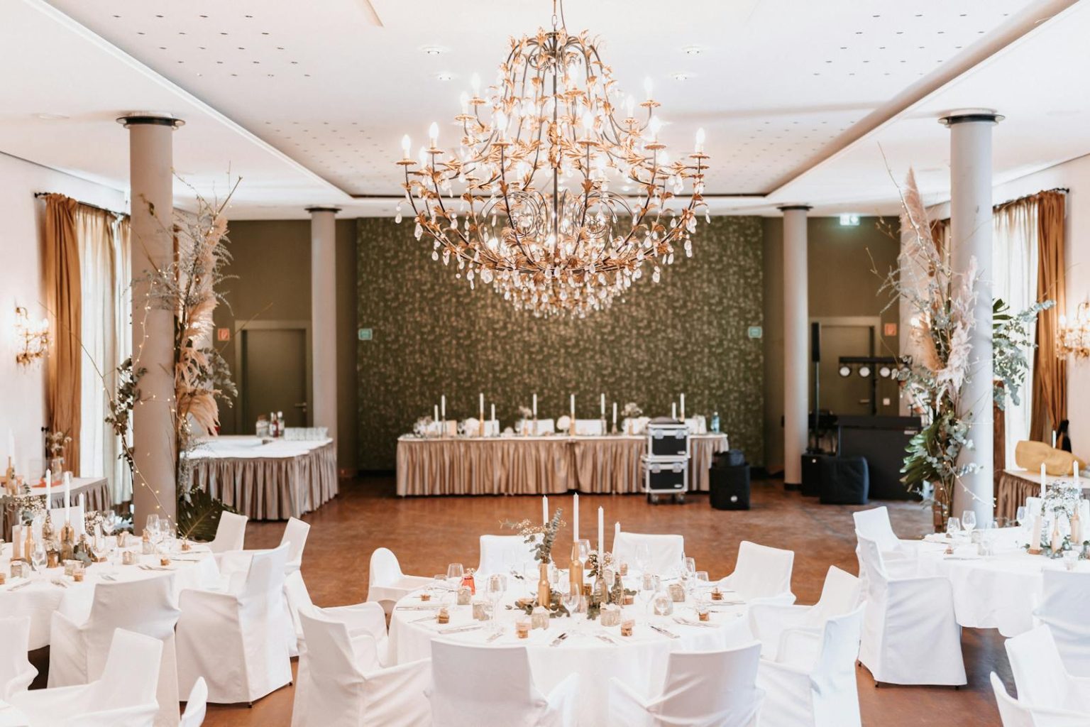 A venue with big ceiling chandelier and white chair in the big hall